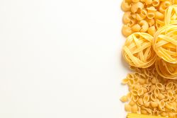 Different pasta on blank background, space for text. Dry uncooked whole pasta