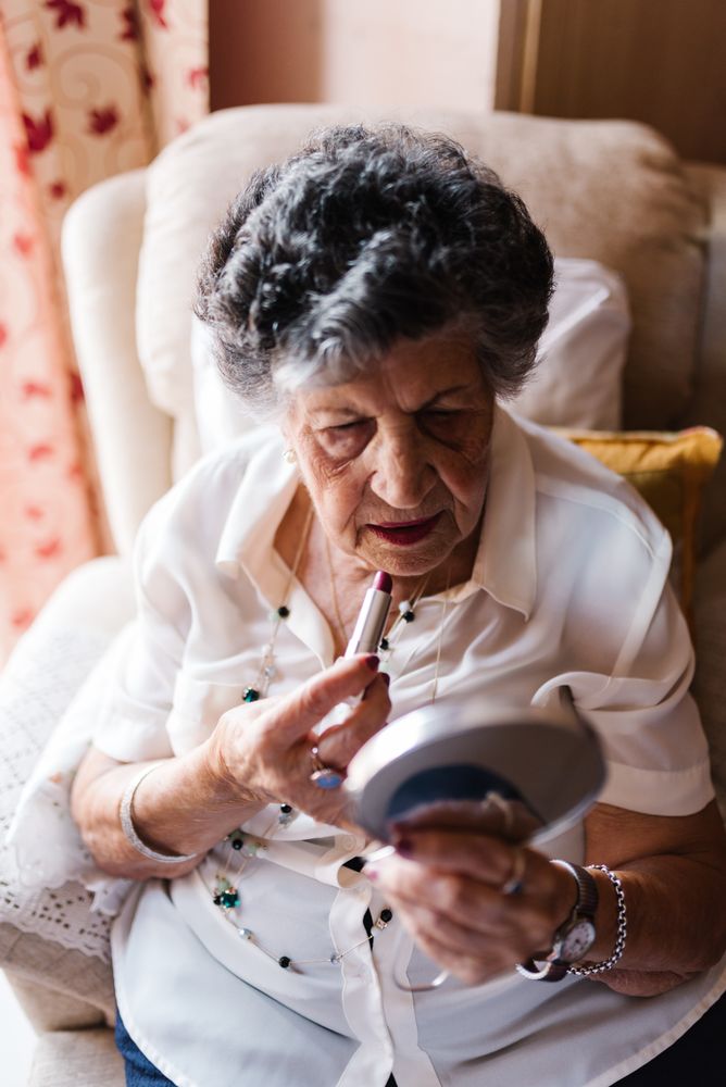Older woman doing lips makeup at home
