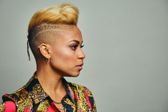 Profile portrait of smiling Black woman posing with short blonde hair in bold patterned shirt