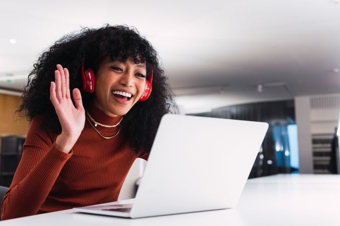 Black female with laptop showing greeting gesture during video call