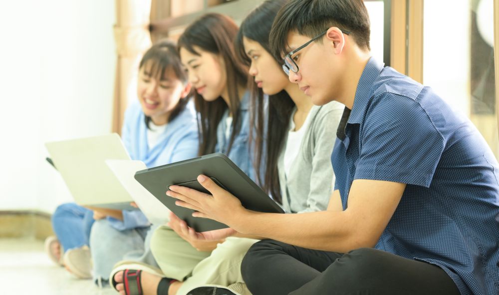 A team of young people sitting on the floor using laptops and tablets.