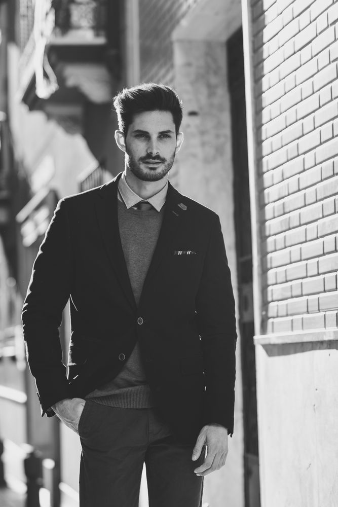 B&W shot of serious man in the street wearing elegant suit with sun in background, vertical