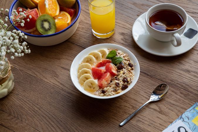 Juice and plate with granola and fruits on table