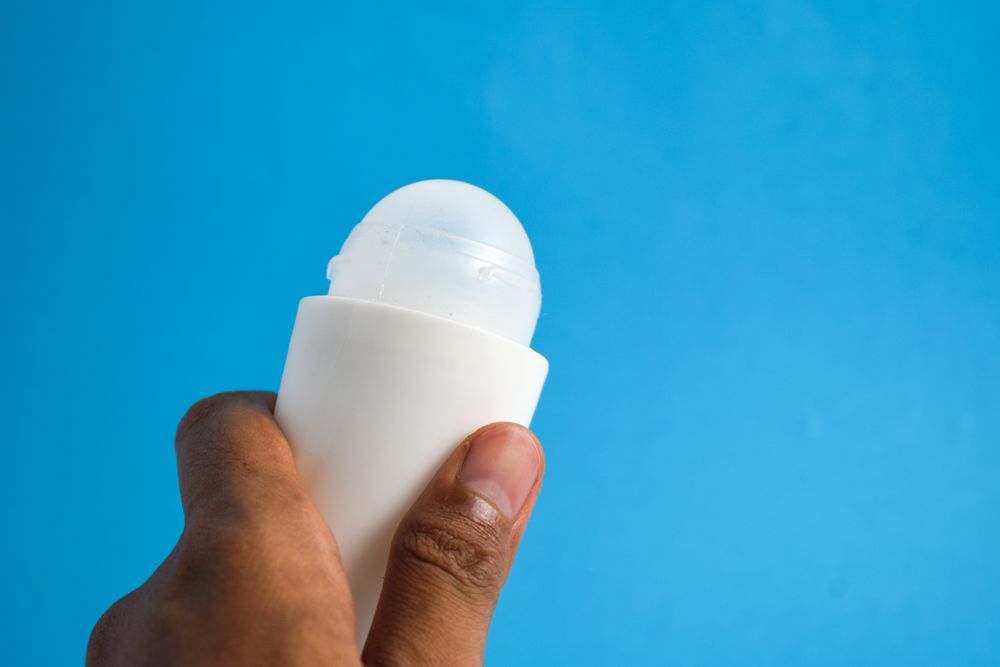 Hand holding a deodorant bottle on blue background