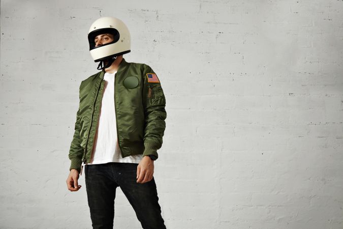 Man in green jacket wearing biker helmet in studio shoot