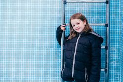 Girl in warm clothes standing in empty pool