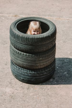 Little girl hiding inside stack of tires