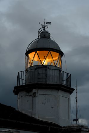 Shining lighthouse against cloudy sky