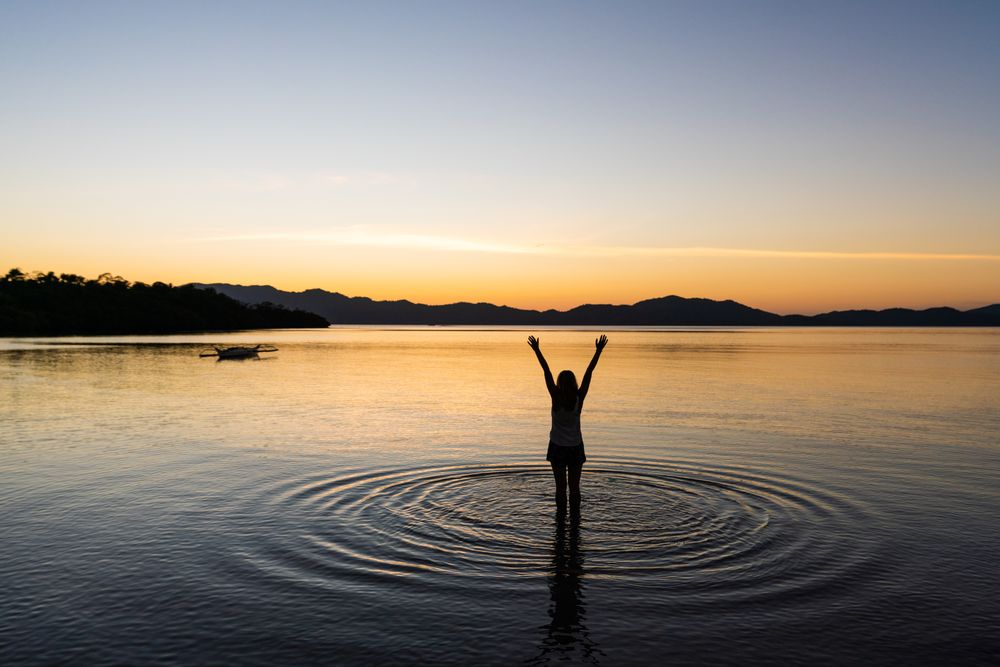 Female standing in lake at sunset