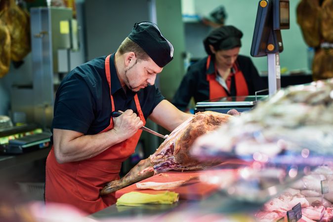Butchers working behind counter with meat