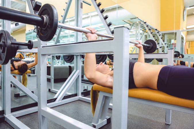 Woman doing bench press in gym
