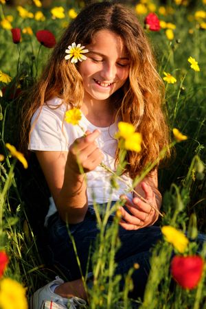 Smiling girl with flower relaxing in meadow