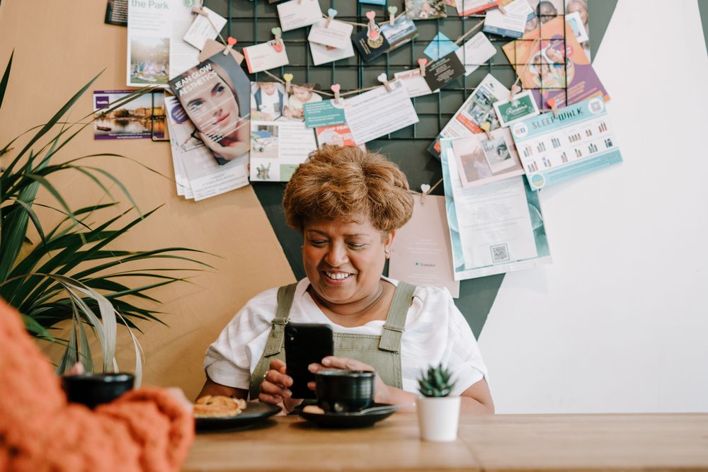 Older Black woman with smart phone at cafe