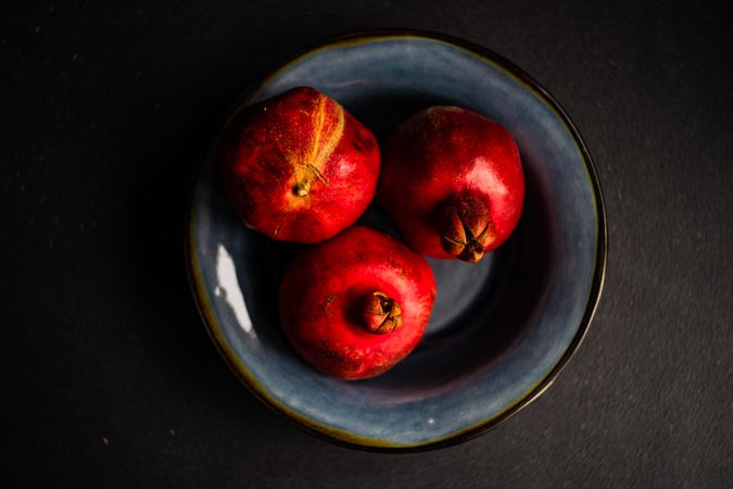 Whole pomegranates in blue fruit bowl