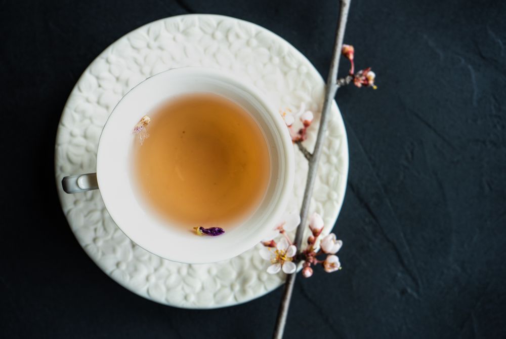 Top view of cup of tea and pink blooming tree