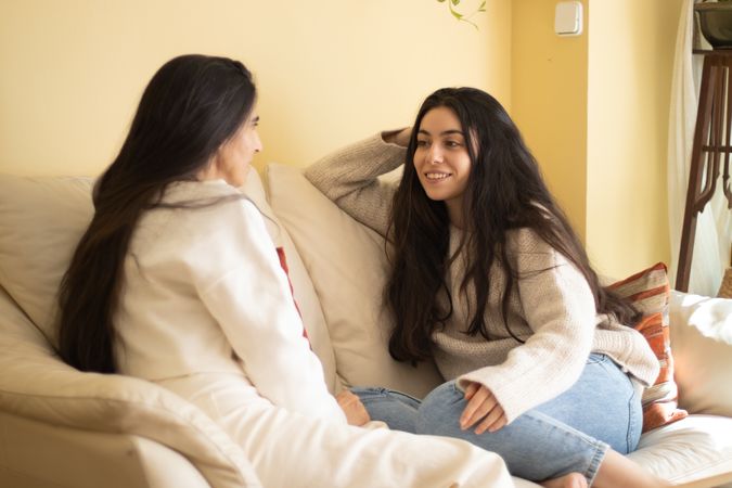 Smiling Young woman talking with her mother sitting on a sofa at home.
