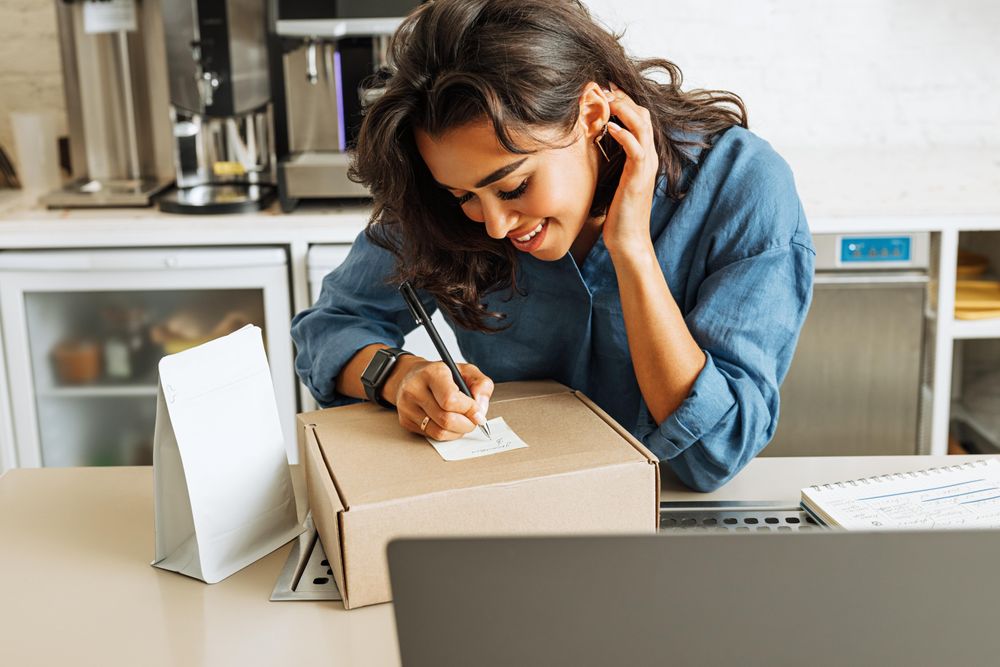 Woman in bright cafe with a box for shipment