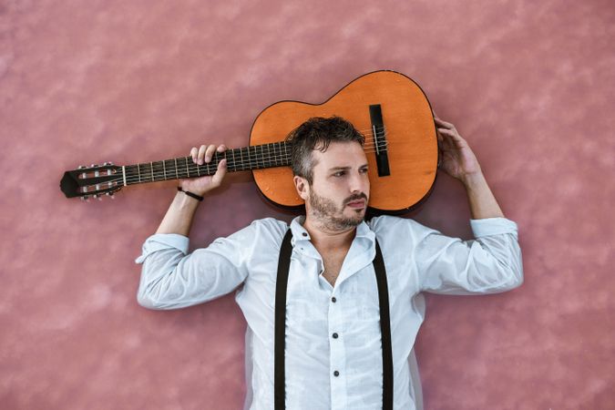 Man resting in water with guitar at seaside