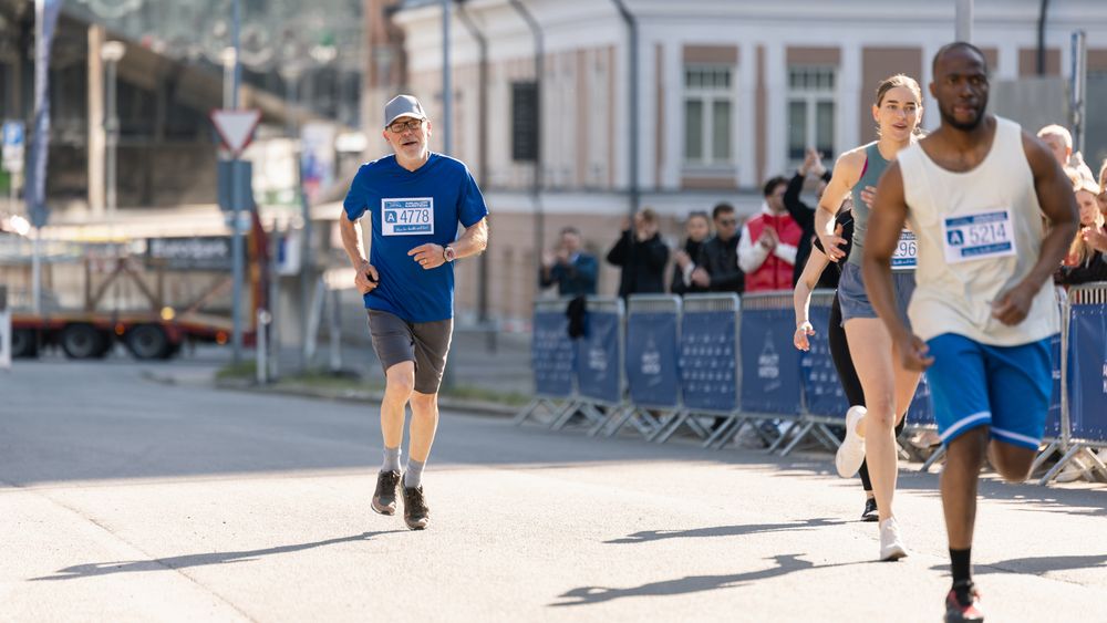 Portrait of a Older Male Jogger Running in a City Marathon and Being Cheered for by the Audience.