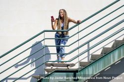 Smiling female skater standing and using phone on stairs, copy space bD3684