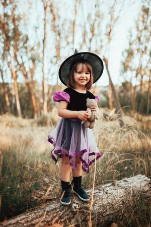 Happy girl standing in the forest in a witch costume