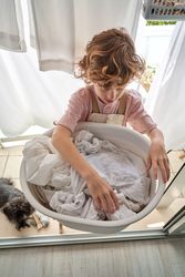 Boy taking sheets from laundry basin on balcony