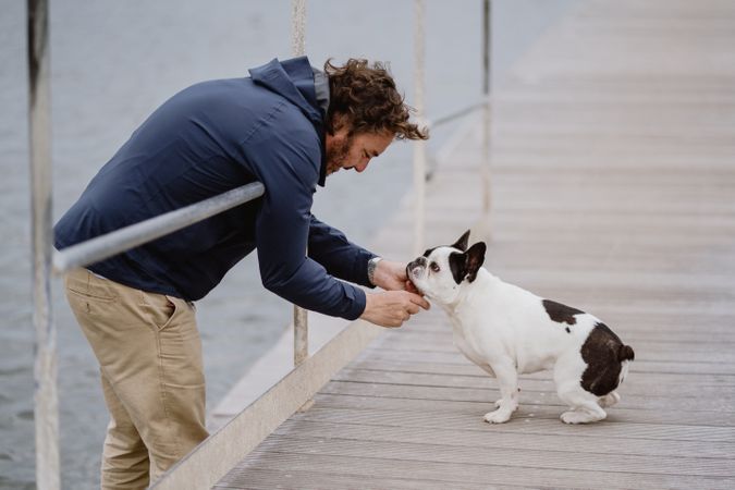 Man petting dog on pier