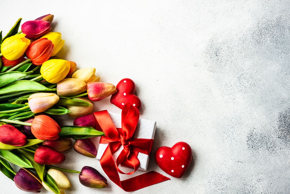 Top view of tulips, dotted heart ornaments and small gift