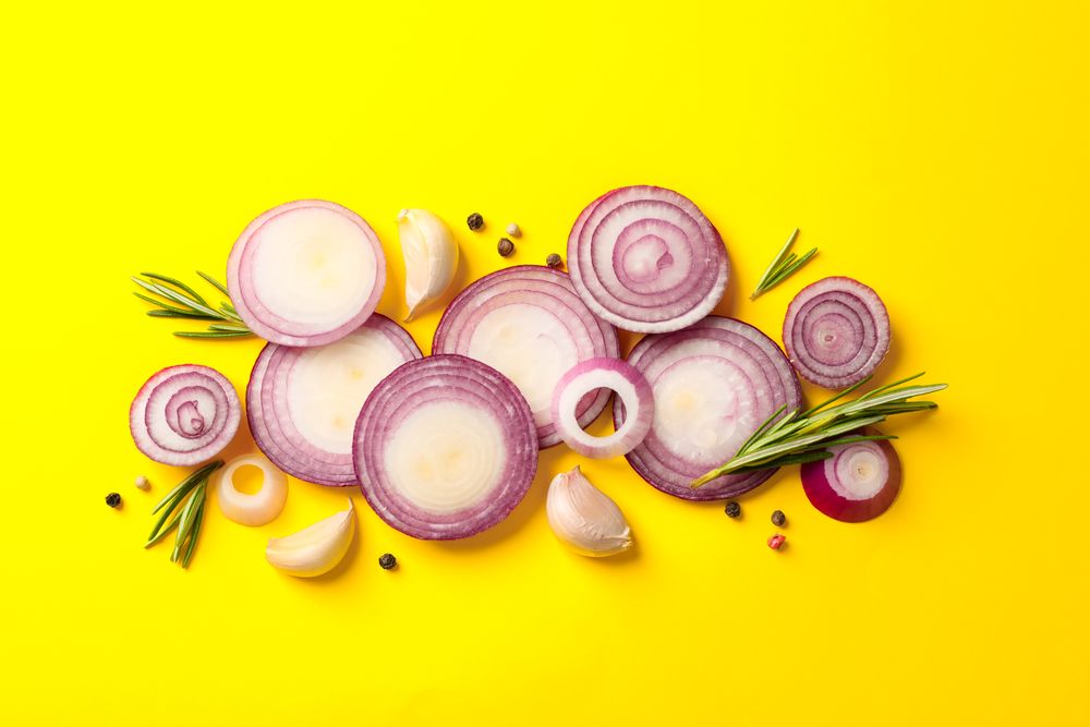 Flat lay composition with red onion rings and spices on color background