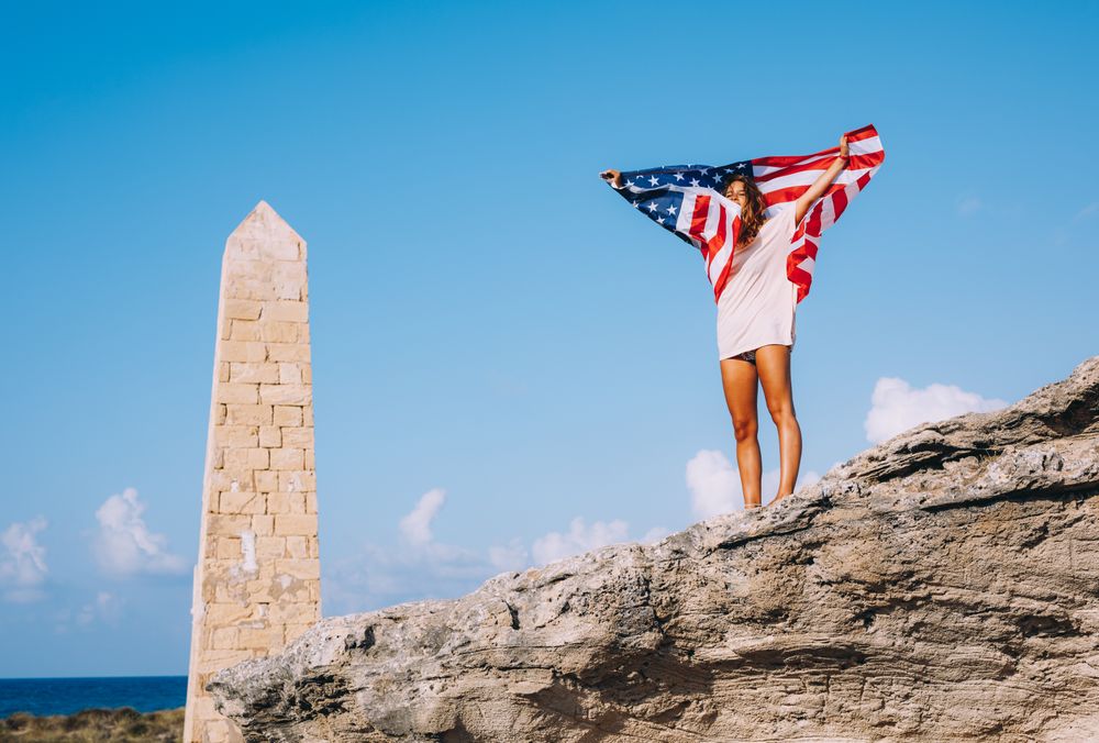 Peaceful patriotic female traveler enjoying in vacation at rocks