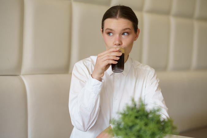Woman in elegant clothes sipping coffee in a cafeteria