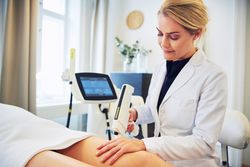 Female cosmetologist performing treatment on legs