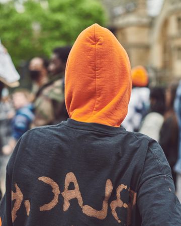 London, England, United Kingdom - June 6th, 2020: Person in black sweater with orange hood