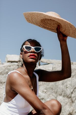 Woman wearing sunglasses blocking the sun with her hat