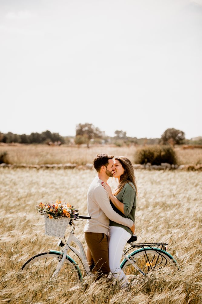 Sincere lovers posing by bicycle on rye field