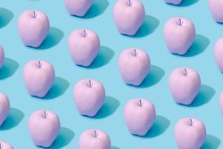 Pattern composition of pink painted apples on pastel blue background