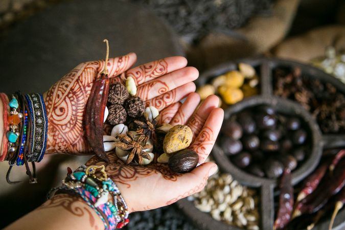 Person's hands with henna tattoo holding dried seeds