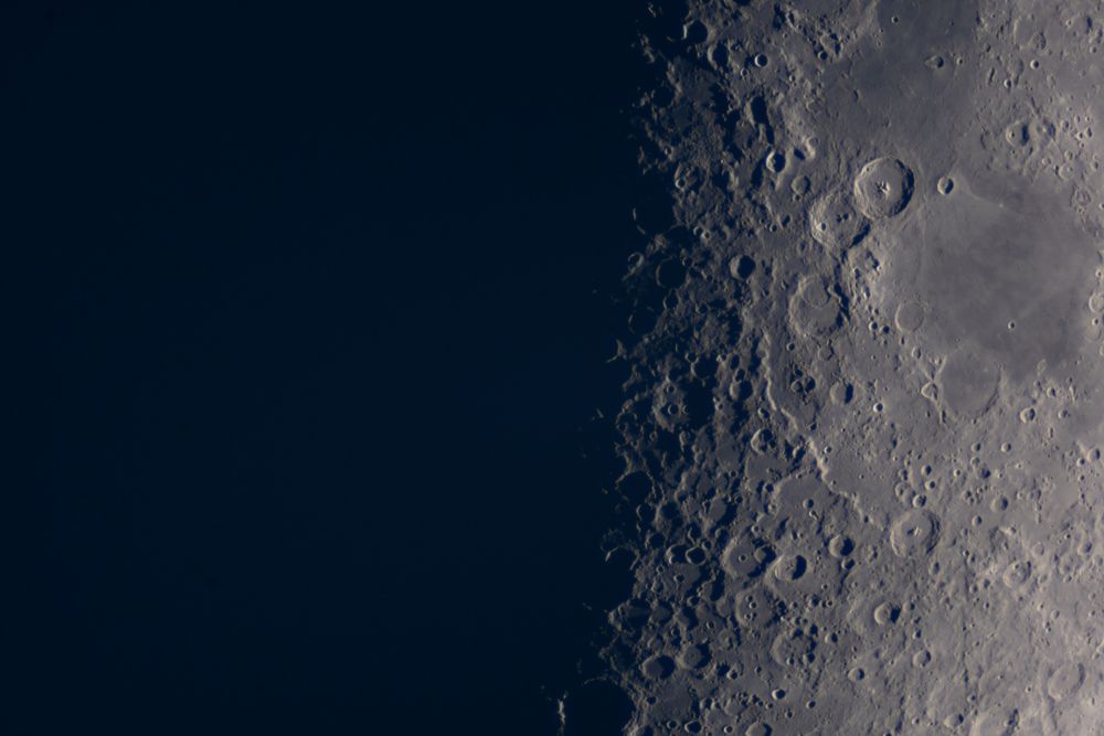 Detailed lunar craters visible near moon's shadow terminator line.