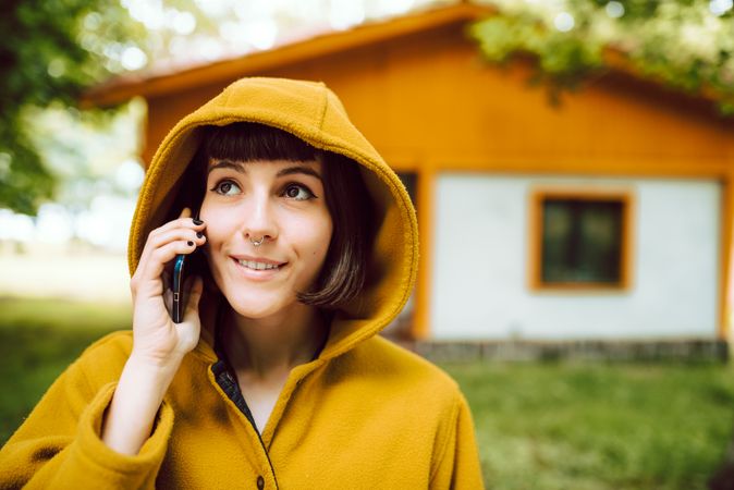 Smiling woman using smartphone near countryside house