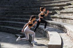 Slim women in sportswear exercising on stairs before doing yoga