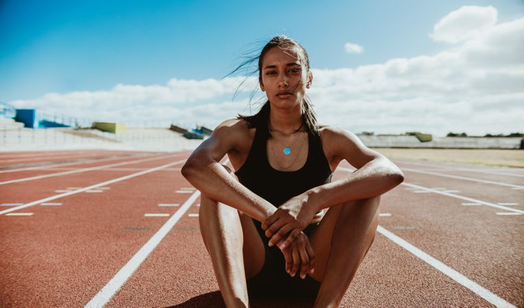 Woman athlete sitting on the track and field stadium