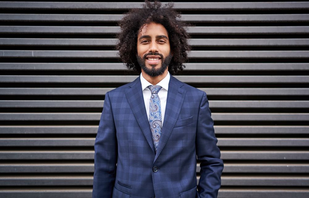 Presentable Black man standing near striped wall
