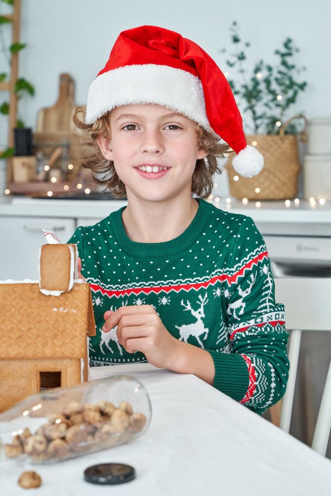 Boy making gingerbread house in kitchen