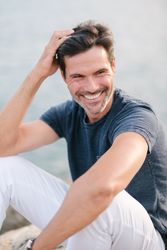 Cheerful man touching head on shore