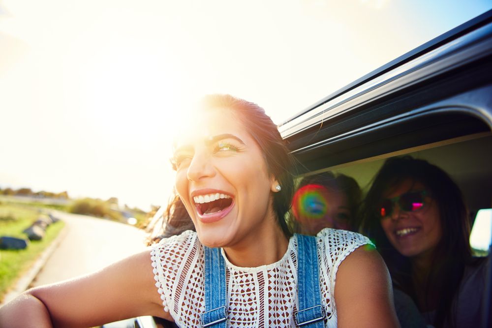 Joyous woman half outside of car window