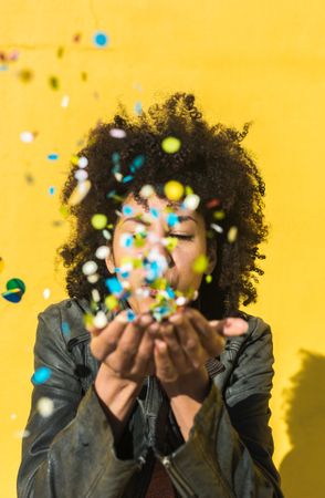 Black woman with afro hair celebrating with confetti.