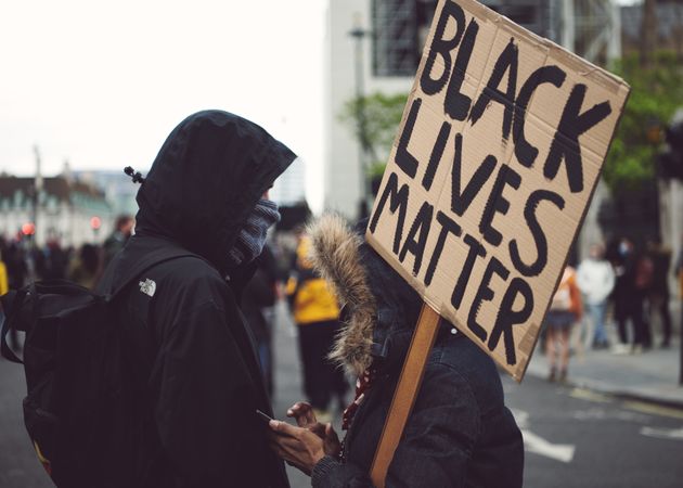 London, England, United Kingdom - June 6th, 2020: Two people in hooded warm coats with sign