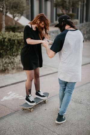Man helping girlfriend to skate on road