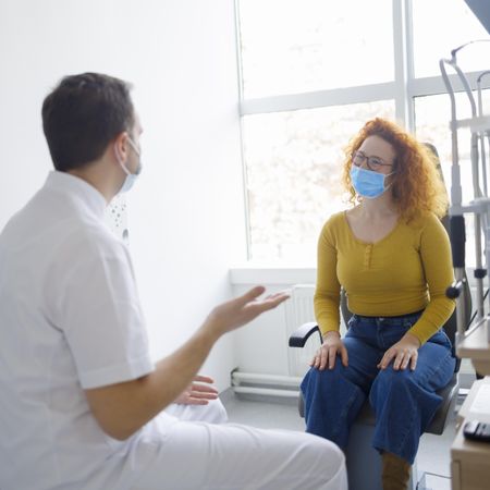 Doctor consulting with patient, both wearing facemasks