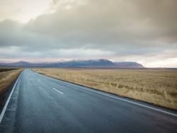 Road running between fields and mountains